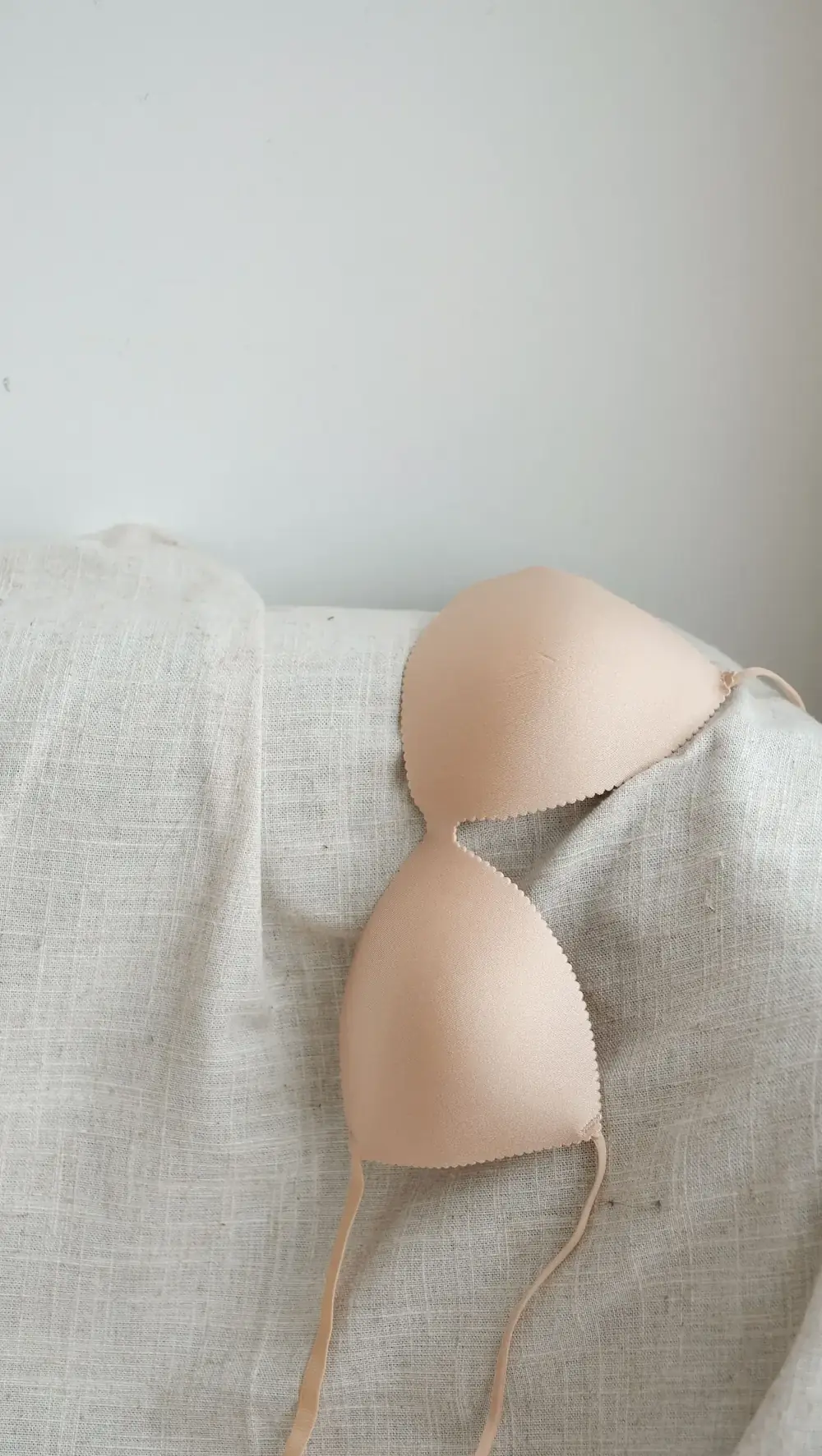 Minimal beige bra displayed against a neutral textile background