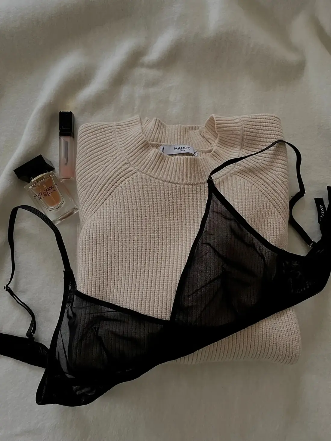 Bra and folded sweater arranged as an everyday clothing flat lay