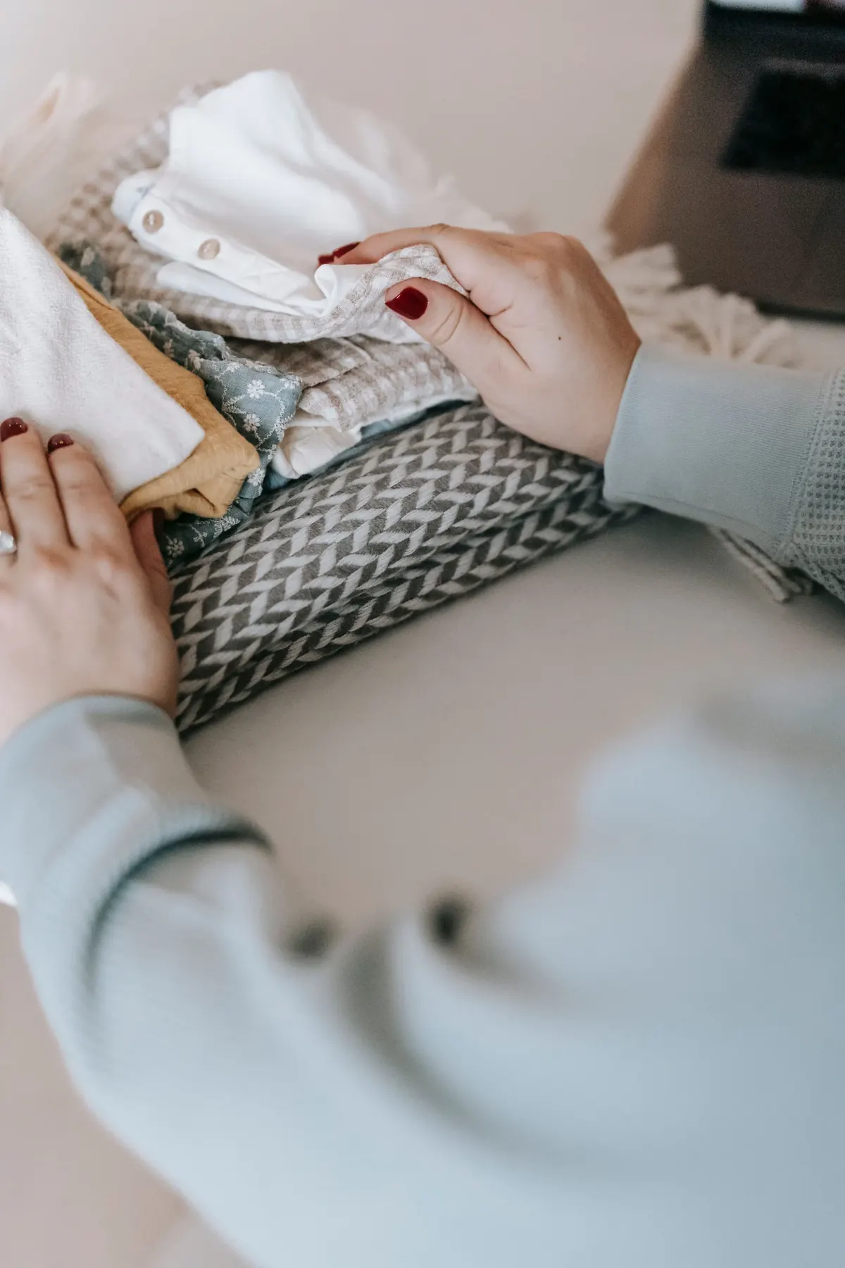 Hands folding and organizing soft clothing in a calm home setting