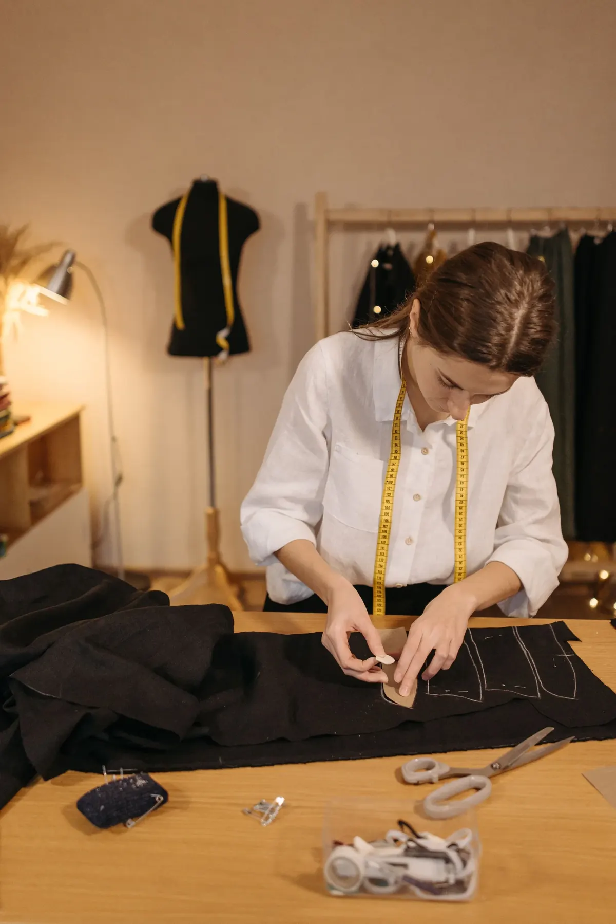 Tailor working with a measuring tape and fabric at a work table