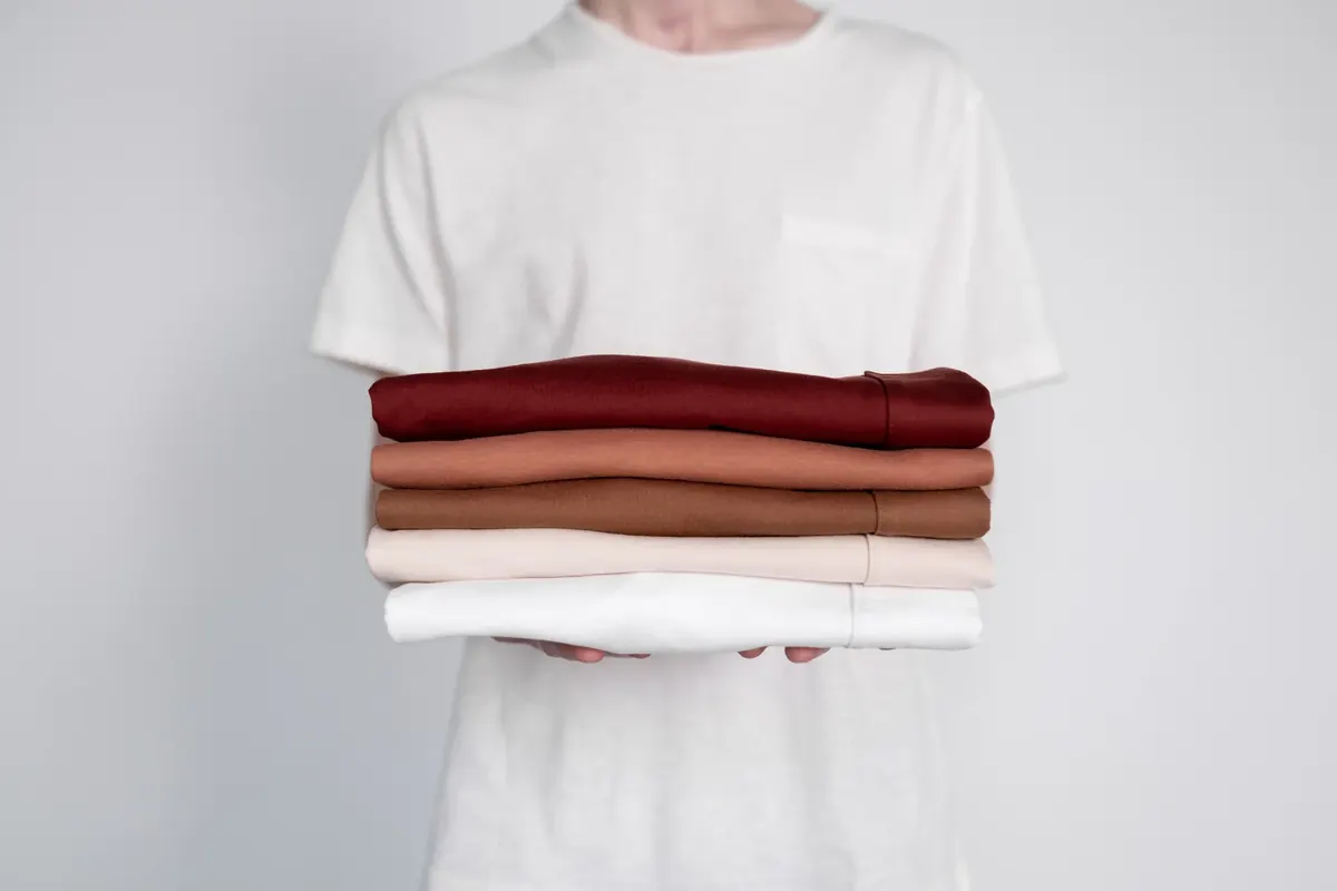 Stack of neatly folded neutral garments held against a simple background