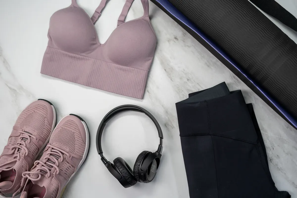 Pink sports bra with shoes, leggings and headphones in a fitness flat lay