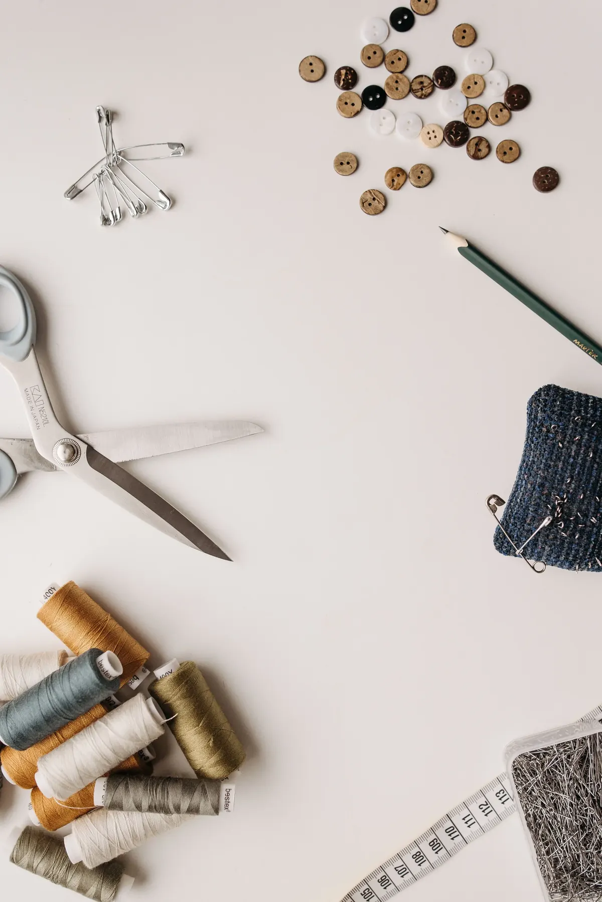 Scissors, thread, buttons and measuring tape in a clean sewing flat lay