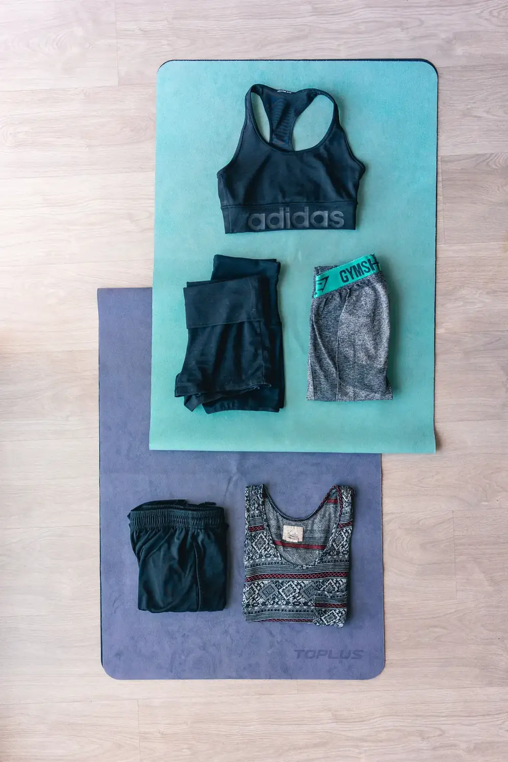 Workout clothes and sports bras arranged on exercise mats
